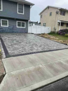 Paved driveway and concrete sidewalk in a residential area, showcasing masonry work by Soft Wind Landscape & Masonry for outdoor transformations in New York.