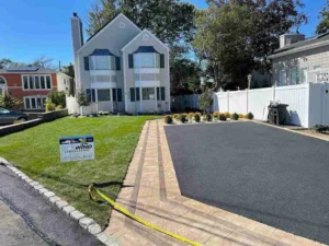New York residential landscape featuring a modern two-story home, manicured lawn, and newly paved driveway with brick edging, showcasing Soft Wind Landscape & Masonry design elements.