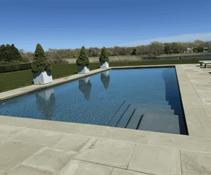 Luxury swimming pool with elegant stone steps and manicured hedges, showcasing Soft Wind Landscape & Masonry's outdoor design expertise in New York.
