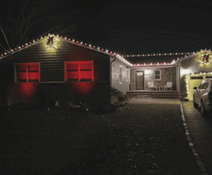 Festively decorated New York home with holiday lights and red accents, showcasing landscape design potential for outdoor transformations.
