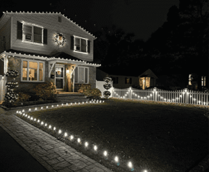 Modern home with elegant landscape lighting and masonry features, showcasing a beautifully designed outdoor space in a nighttime setting.