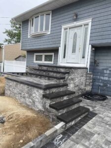 Masonry steps leading to a modern home entrance, showcasing custom stonework and landscaping design by Soft Wind Landscape & Masonry in New York.