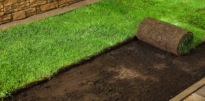 Freshly rolled sod being installed on a prepared soil bed, showcasing landscape transformation by Soft Wind Landscape & Masonry.